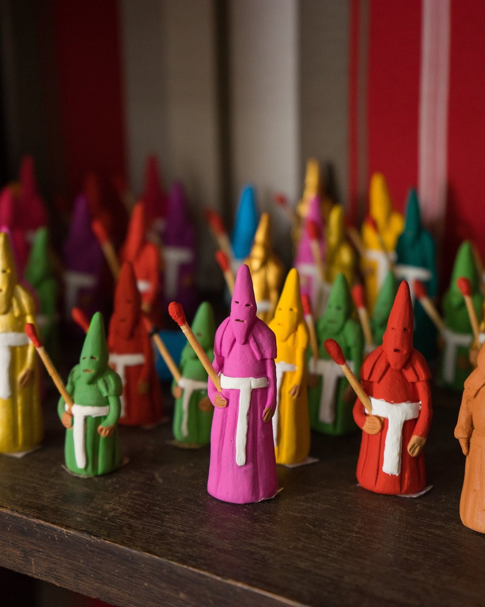 Miniaturas de farricocos em cerâmica pintada, de capuz pontudo rosa, verde, amarelo, vermelho e laranja, segurando pequenas tochas, enfileiradas na prateleira de uma loja de artesanato da Cidade de Goiás.