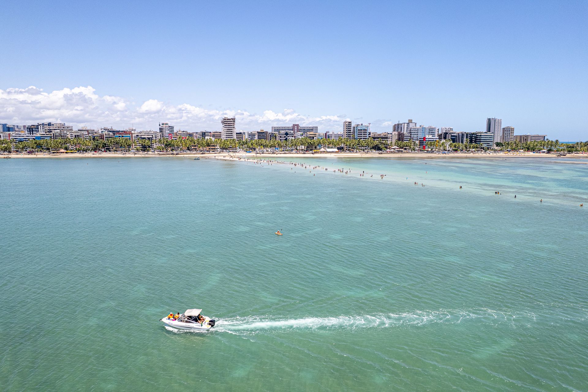 Vista aérea de um barco navegando sobre as piscinas naturais na orla de Maceió