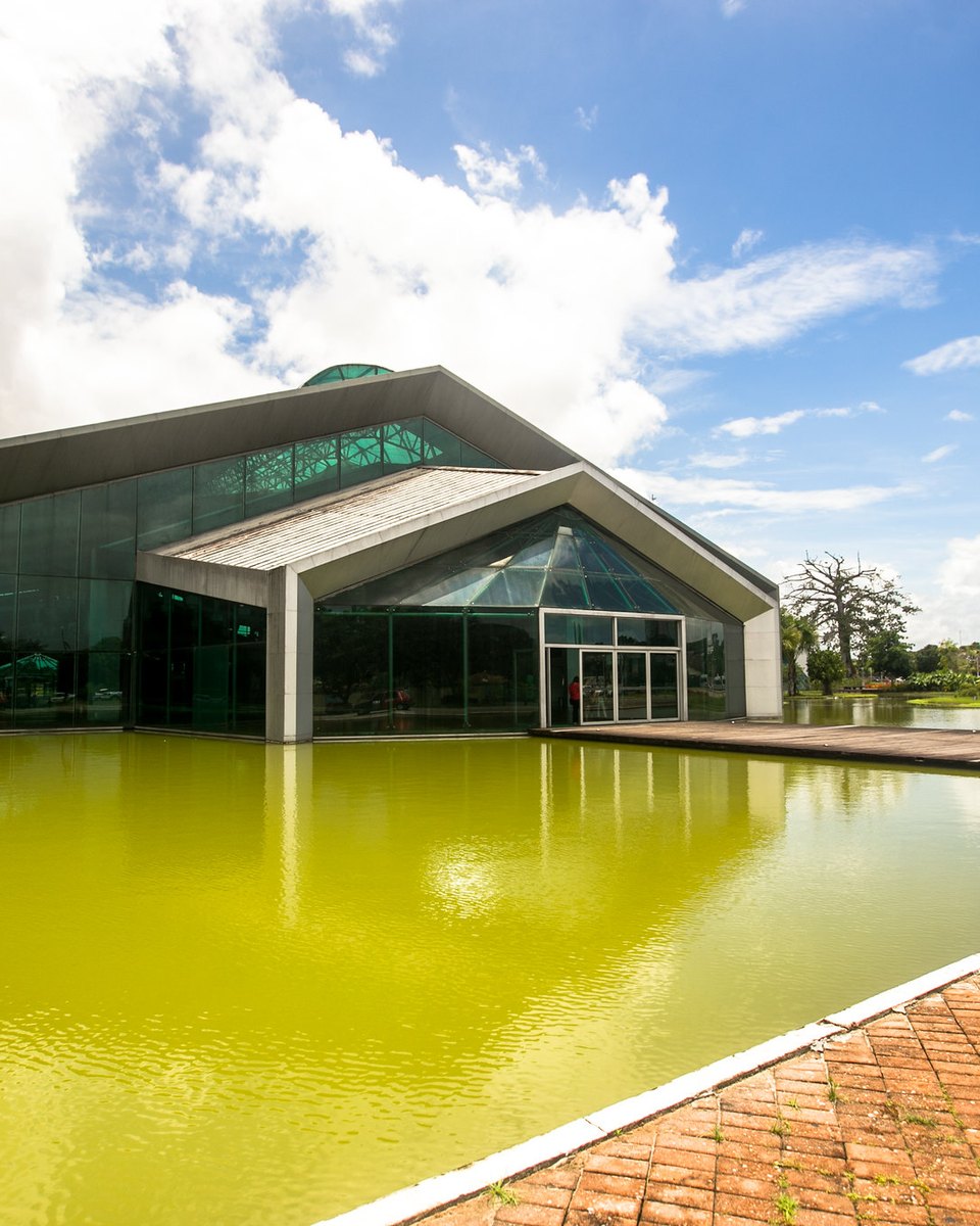 Fachada de vidro do Hangar Centro de Convenções da Amazônia, em Belém, refletida no espelho d'água em frente ao prédio.
