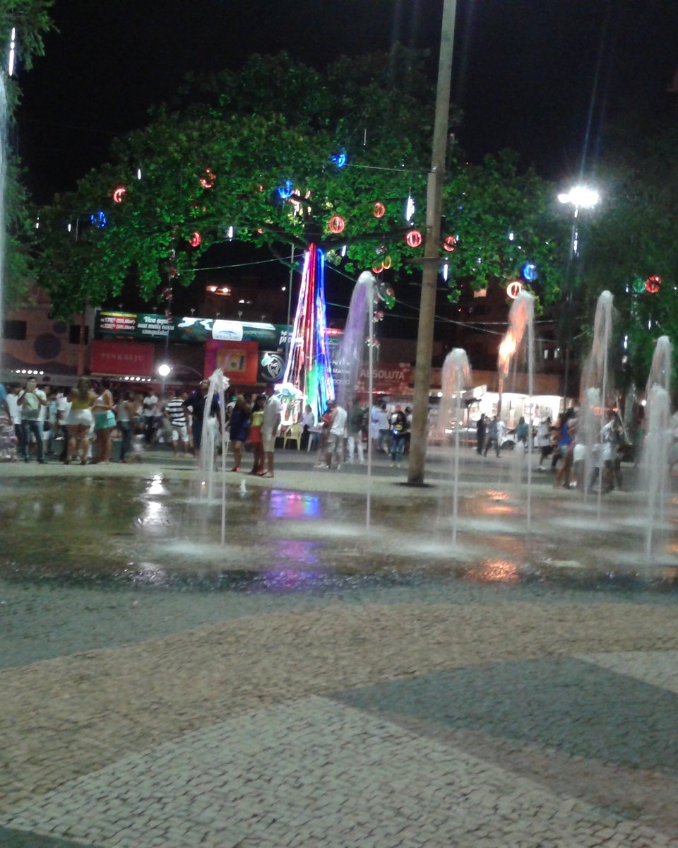Praça no Centro de Caldas Novas à noite, com fontes de água e luzes coloridas.