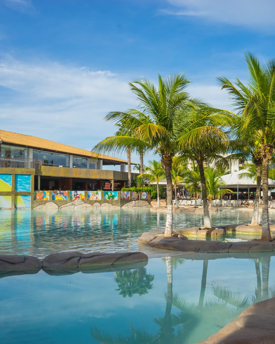 Piscina de água quente do Náutico Praia Clube, em Caldas Novas, com coqueiros refletidos na água.