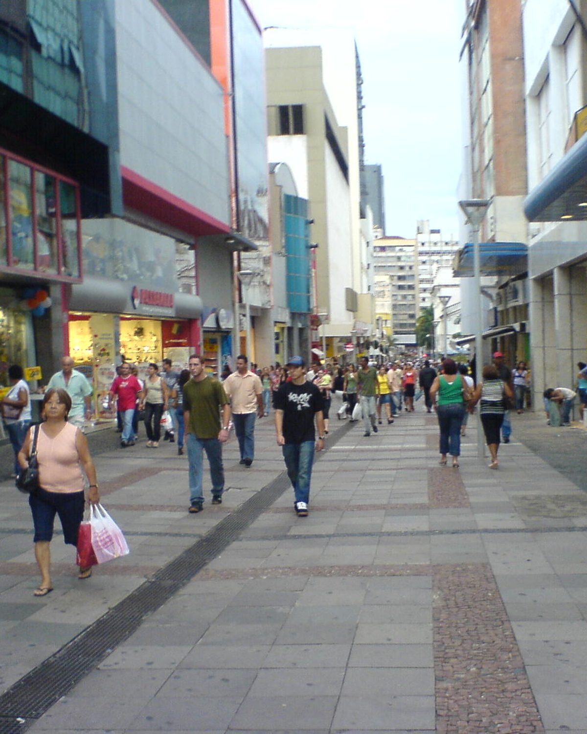Pessoas caminhando com sacolas de compras no calçadão da Rua 13 de Maio, no centro de Campinas.