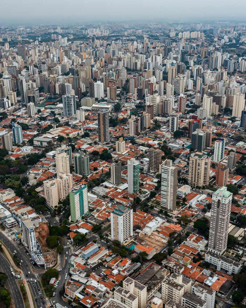 Vista aérea dos prédios altos do Cambuí e do centro de Campinas, com casas de telhado baixo entre as torres.