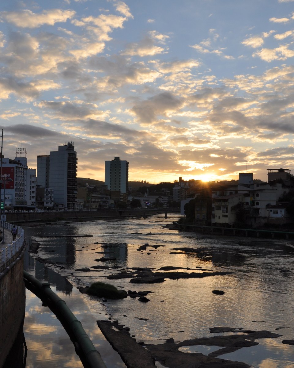 Pôr do sol sobre o Rio Itapemirim com a avenida beira-rio e os prédios de Cachoeiro de Itapemirim.