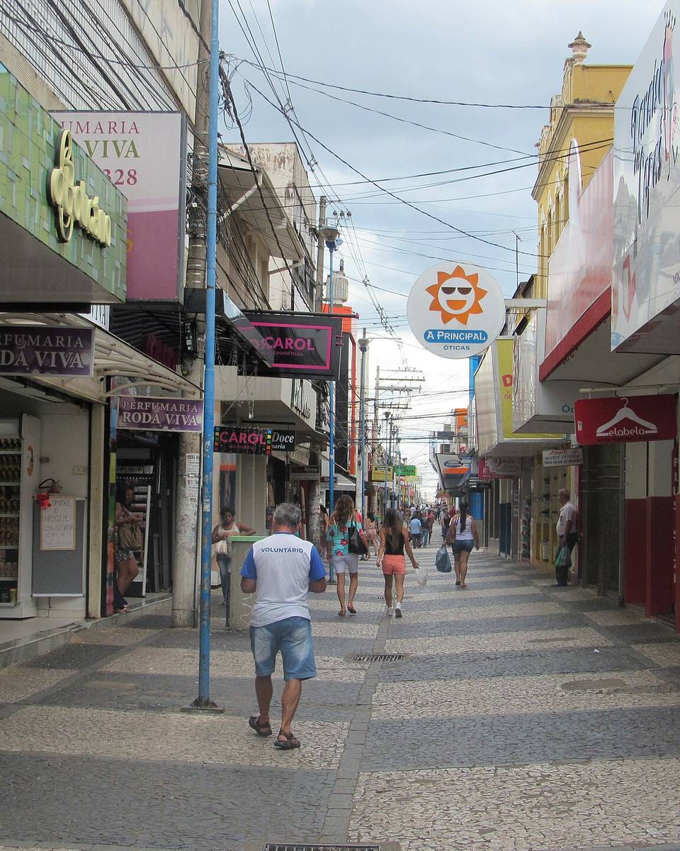 Calçadão da Rua do Comércio, no Centro de Franca, com pessoas caminhando e olhando vitrines de lojas dos dois lados.