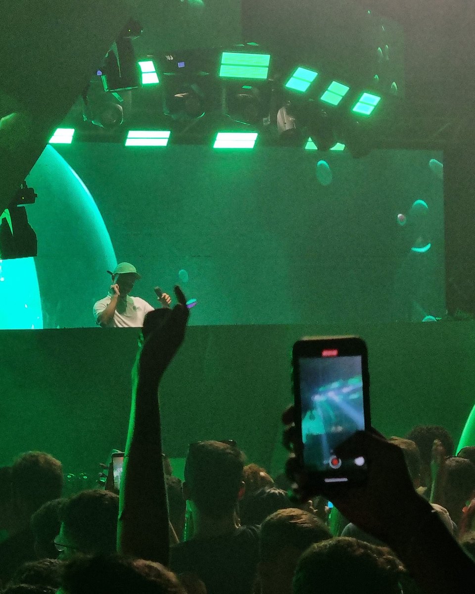 Público de um show em Goiânia com os celulares erguidos gravando o palco iluminado de verde.