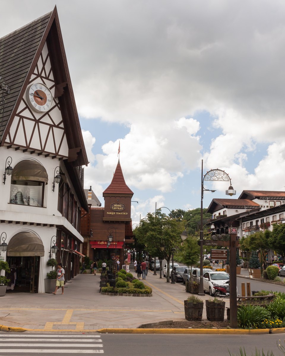 Prédio em estilo enxaimel numa esquina do centro de Gramado, com faixa de pedestres e canteiros de flores.