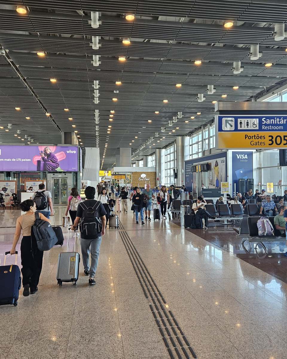 Passageiros puxando malas pelo saguão de embarque do Terminal 3 do Aeroporto de Guarulhos.