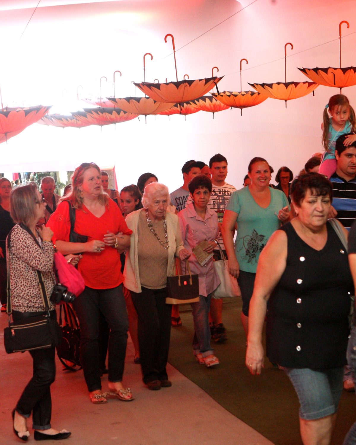 Visitantes caminhando por um corredor decorado com guarda-chuvas na Festa das Flores, em Joinville.