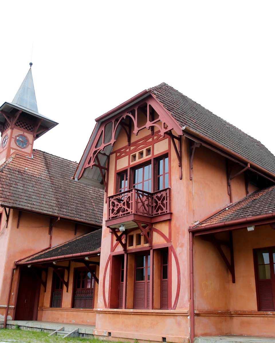 Estação da Memória, antiga estação ferroviária de Joinville, em estilo enxaimel com paredes cor de tijolo, torre com relógio e varanda de madeira, cercada de gramado e árvores.