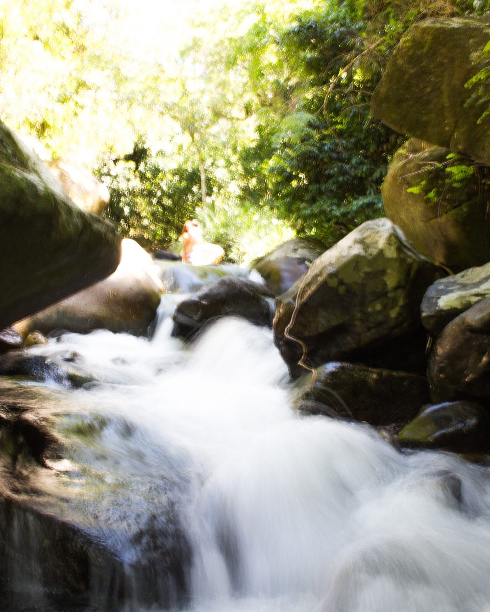 Cachoeira do Sana, em Macaé, com a água correndo entre pedras e a mata ao redor.