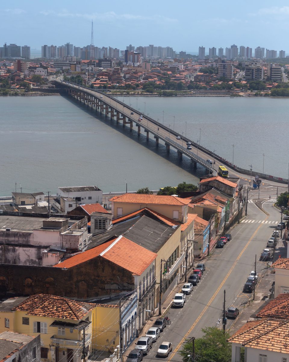 Ponte do São Francisco sobre o rio Anil em São Luís, vista do alto do centro histórico, com telhados coloniais e carros na rua em primeiro plano e os prédios da outra margem ao fundo