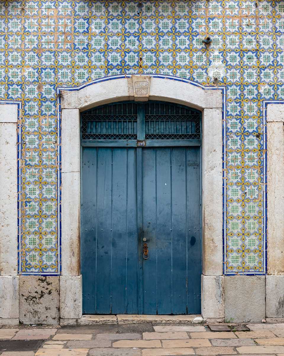 Fachada de casarão na Rua Portugal revestida de azulejos portugueses azuis e amarelos, com três portas de madeira azul em arco