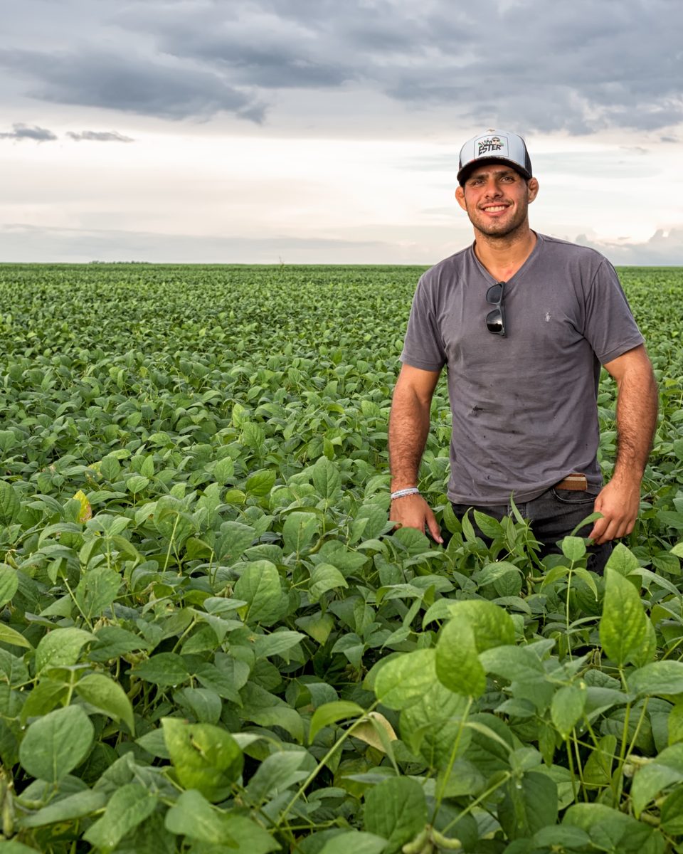 Produtor de boné em pé no meio de uma lavoura de soja verde que se estende até o horizonte, nos Gerais de Balsas, no sul do Maranhão, sob um céu carregado