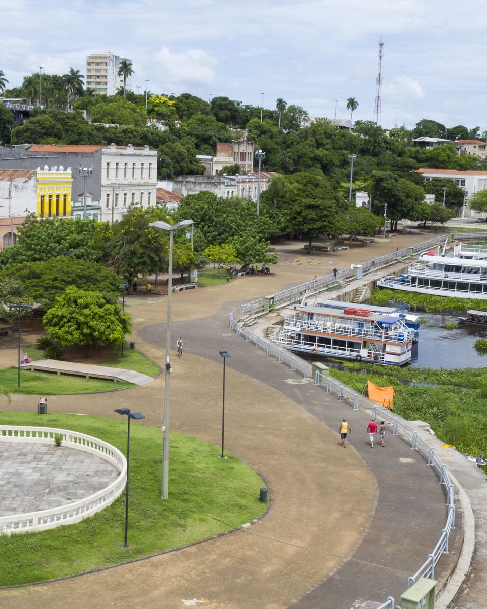 Orla do rio Paraguai em Corumbá, com barcos atracados, o calçadão à beira do rio e o casario do centro histórico ao fundo.