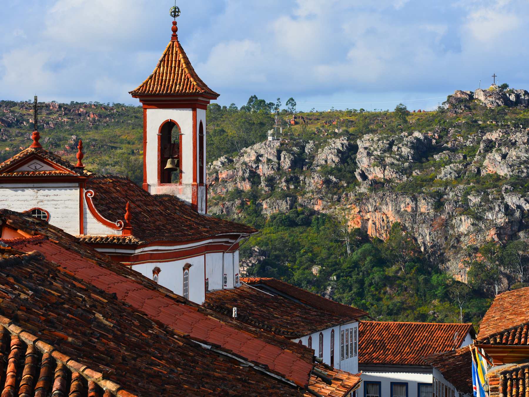 Torre da Igreja de Nossa Senhora do Carmo sobre os telhados coloniais de Diamantina, com a Serra do Espinhaço ao fundo.
