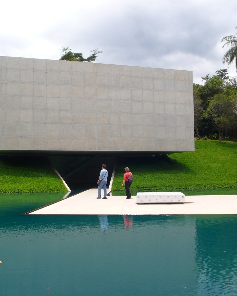 Dois visitantes na plataforma sobre o espelho d'água da Galeria Adriana Varejão, um bloco de concreto suspenso entre o gramado e a mata do Inhotim, em Brumadinho.