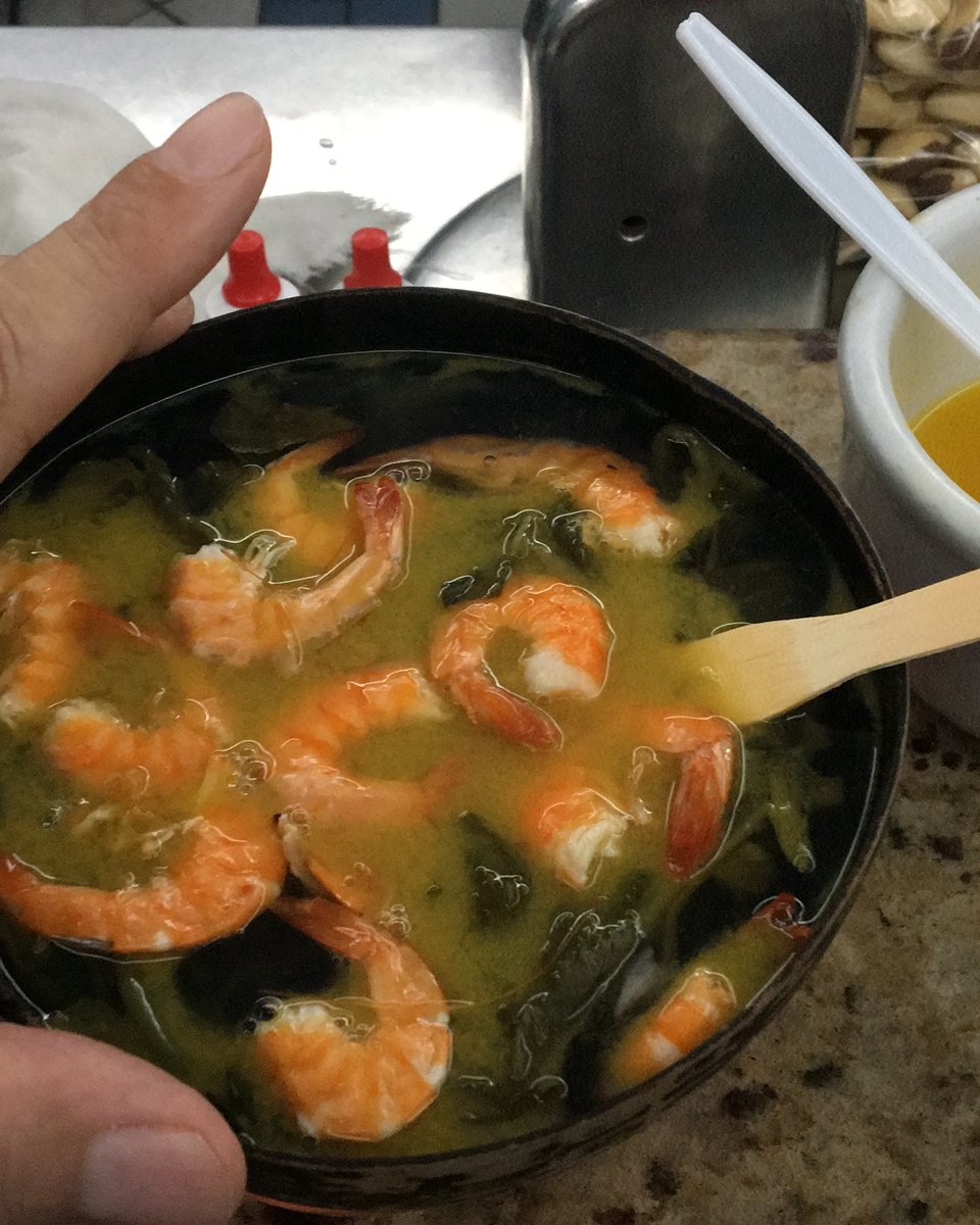 Tacacá servido na cuia, com camarão seco, jambu e goma, e uma tigelinha de tucupi ao lado.