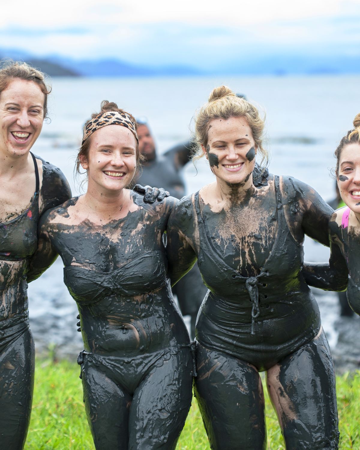 Mulheres cobertas de lama na beira do mar, no Bloco da Lama de Paraty.
