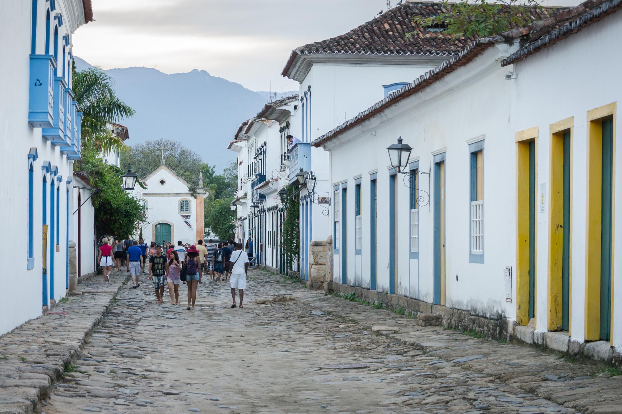 Turistas caminhando por uma rua de pedras do centro histórico de Paraty.