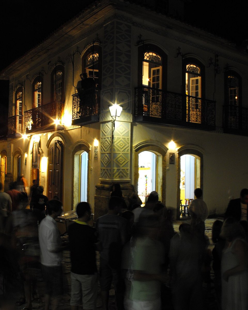 Gente reunida à noite numa rua do centro histórico de Paraty, diante de um casarão iluminado.