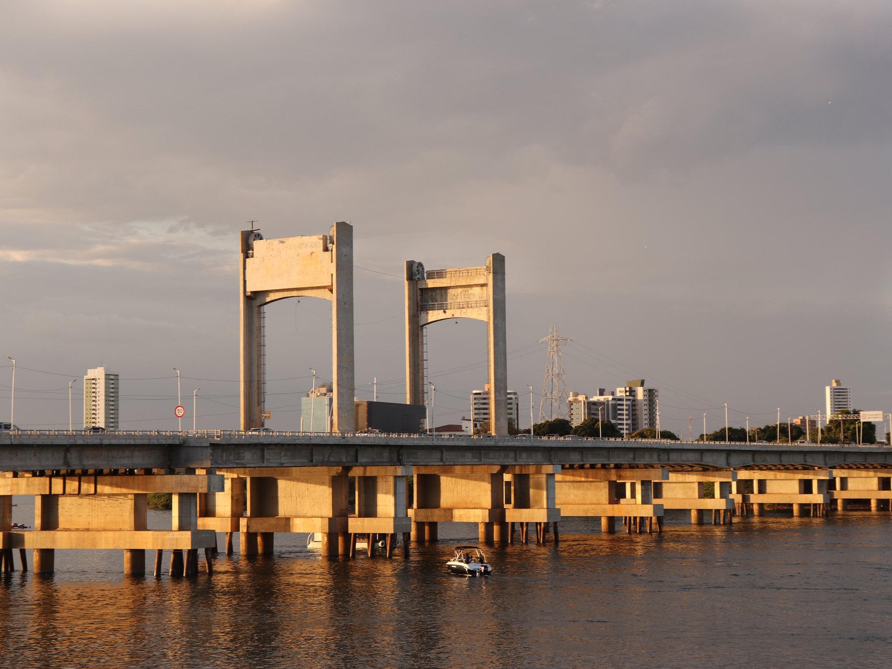 Ponte Presidente Dutra sobre o Rio São Francisco ao entardecer, com as duas torres de concreto, a luz dourada na água e a cidade ao fundo.