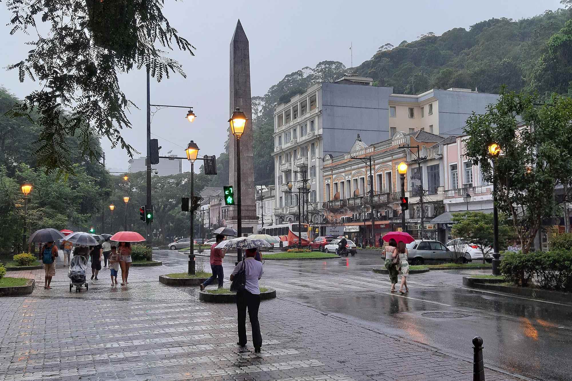 Praça do centro histórico de Petrópolis com postes de luz acesos no fim de tarde.