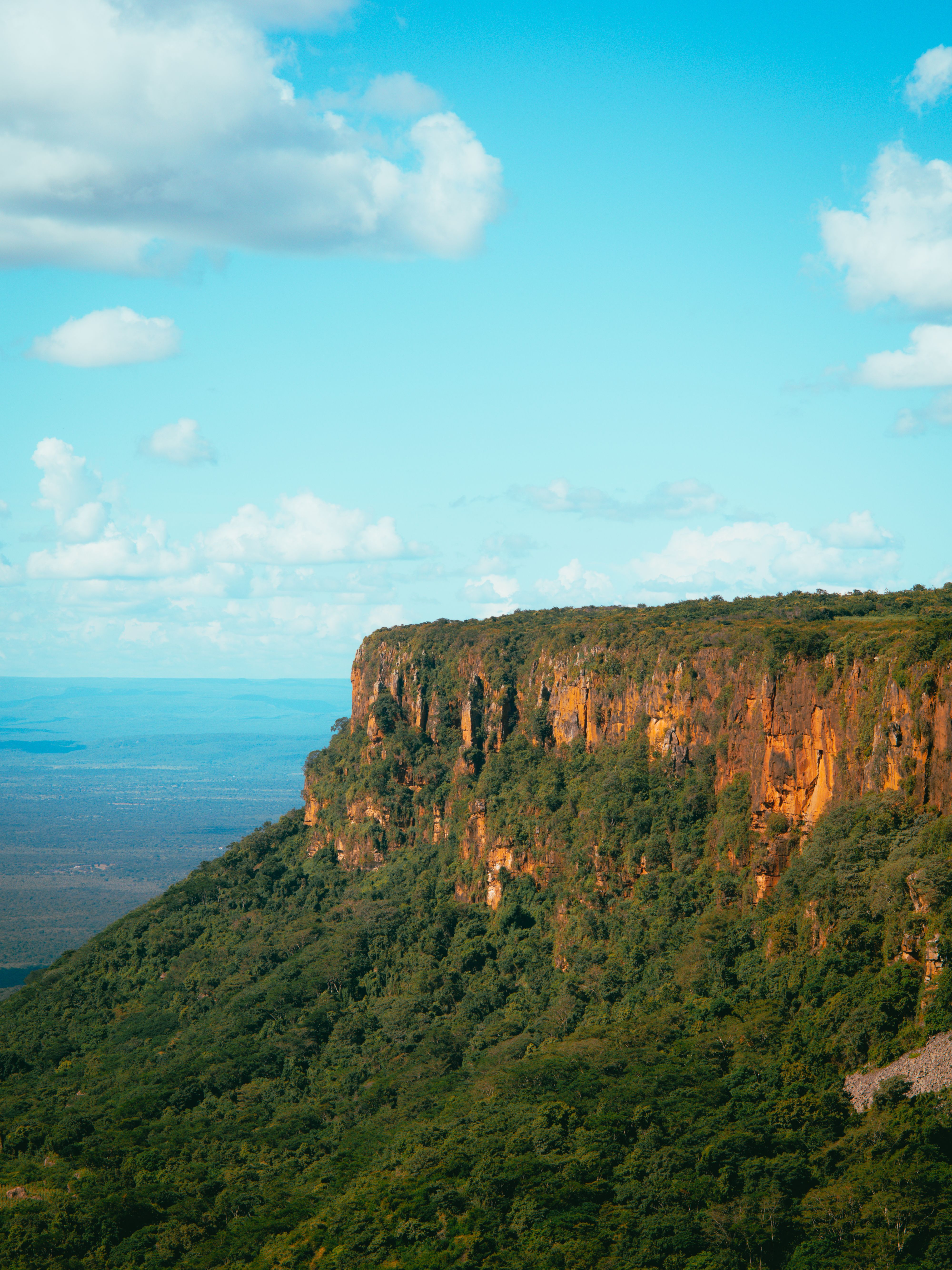 Penhasco verde e formação rochosa do Mirante do Gritador sob céu azul, em Pedro II
