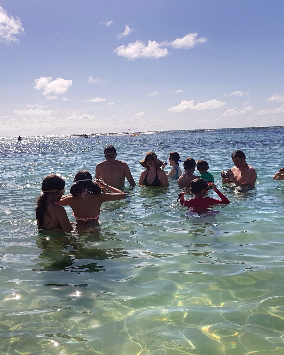 Banhistas com água pela cintura nas piscinas naturais de Porto de Galinhas.