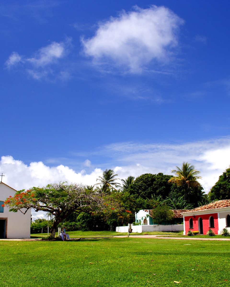 Quadrado de Trancoso com a igreja branca e as casas coloridas em volta do gramado.