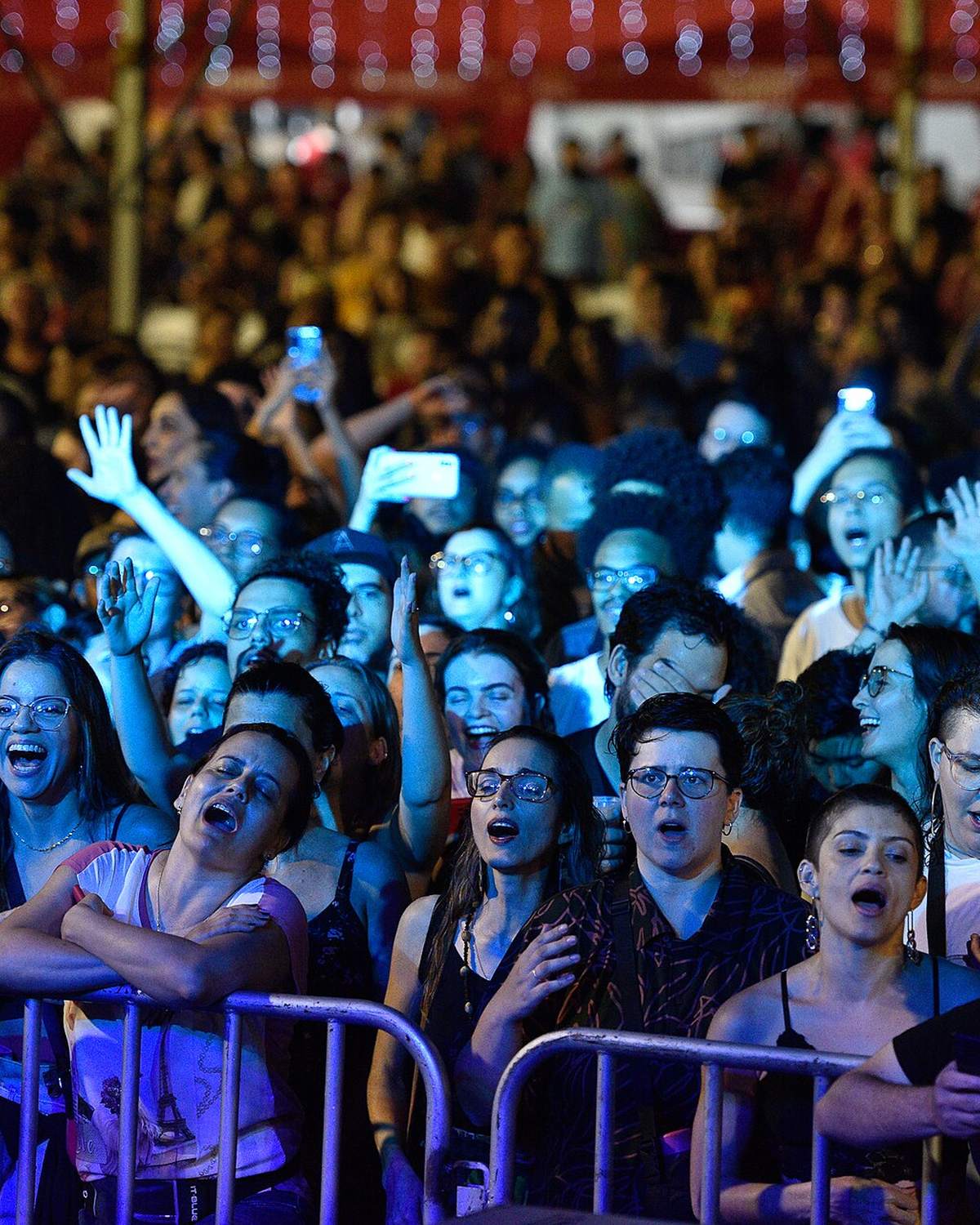 Público cantando na grade de um show à noite em Presidente Prudente, com celulares filmando o palco.