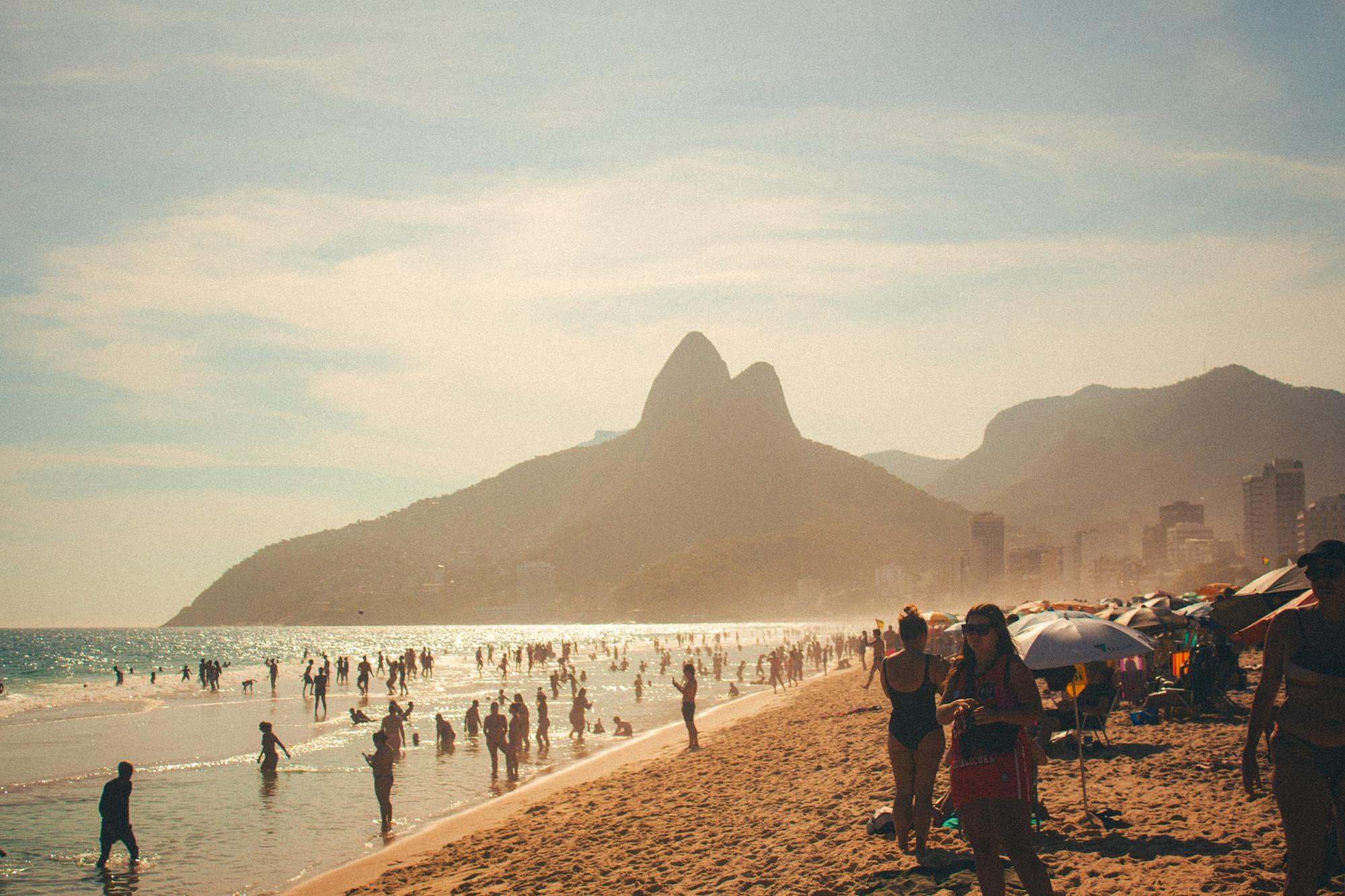 Banhistas na praia de Ipanema numa tarde de sol, com o Morro Dois Irmãos ao fundo.