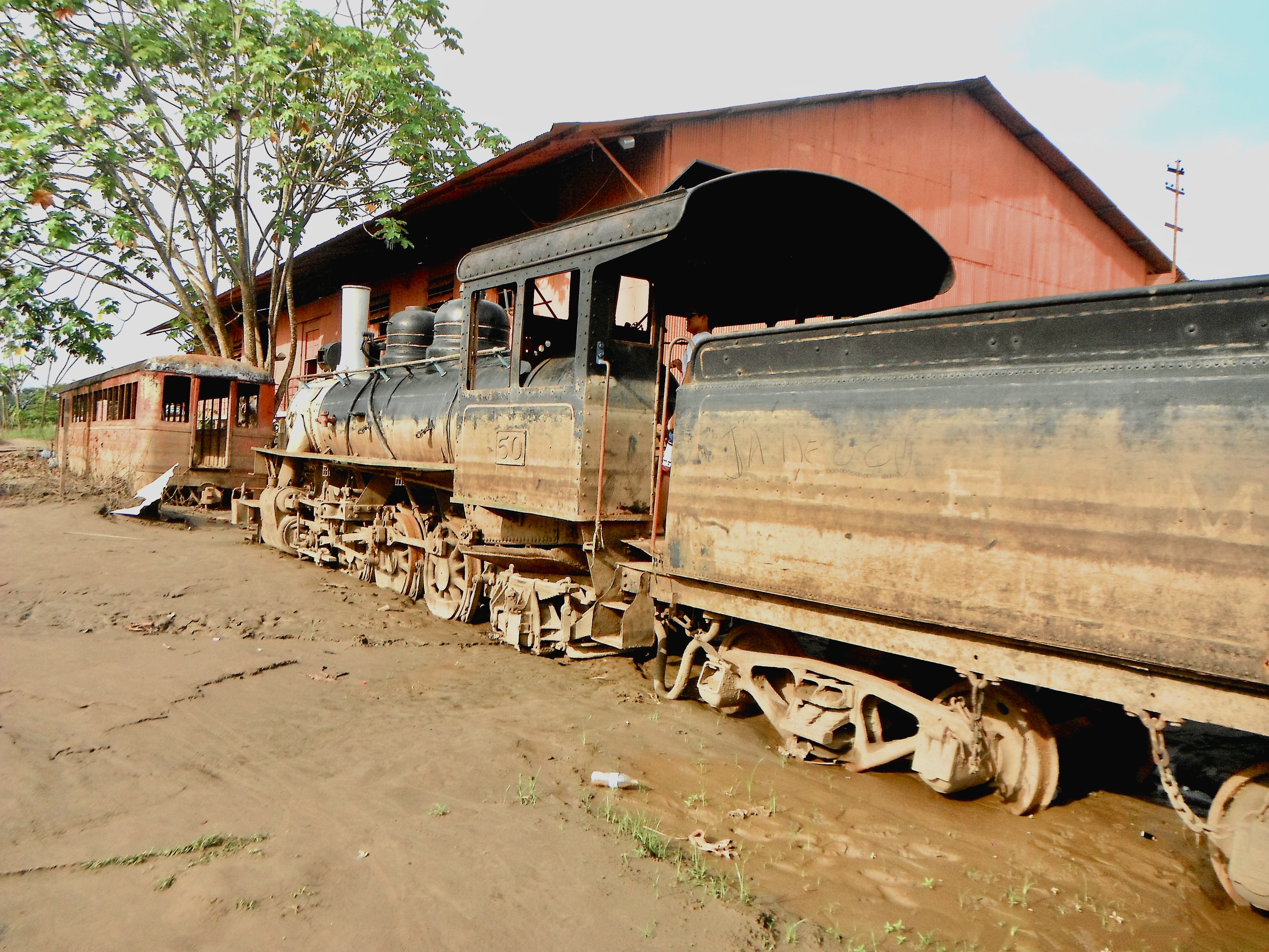 Locomotiva a vapor da Estrada de Ferro Madeira-Mamoré parada nos trilhos, com o prédio histórico ao fundo, em Porto Velho