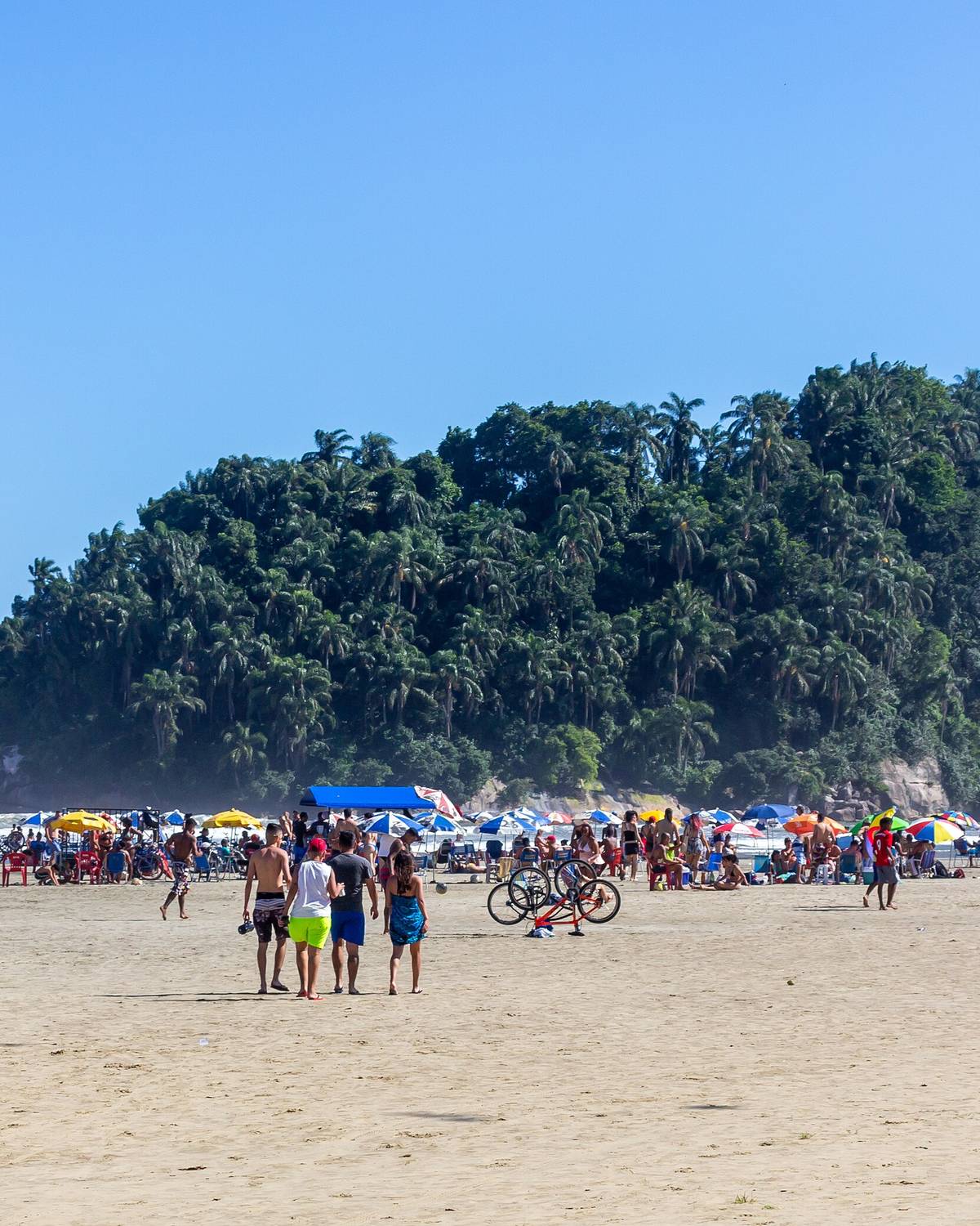 Banhistas e guarda-sóis na Praia do José Menino, em Santos, com a Ilha Urubuqueçaba ao fundo.