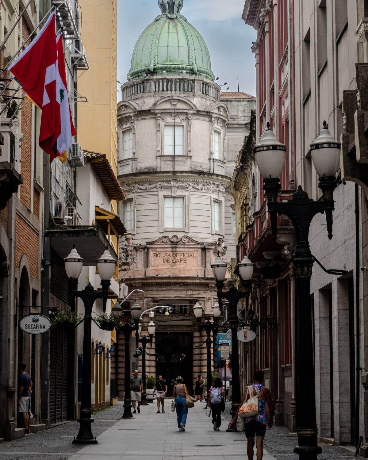 Pedestres na Rua XV de Novembro, no Centro Histórico de Santos, com a torre da Bolsa do Café ao fundo.