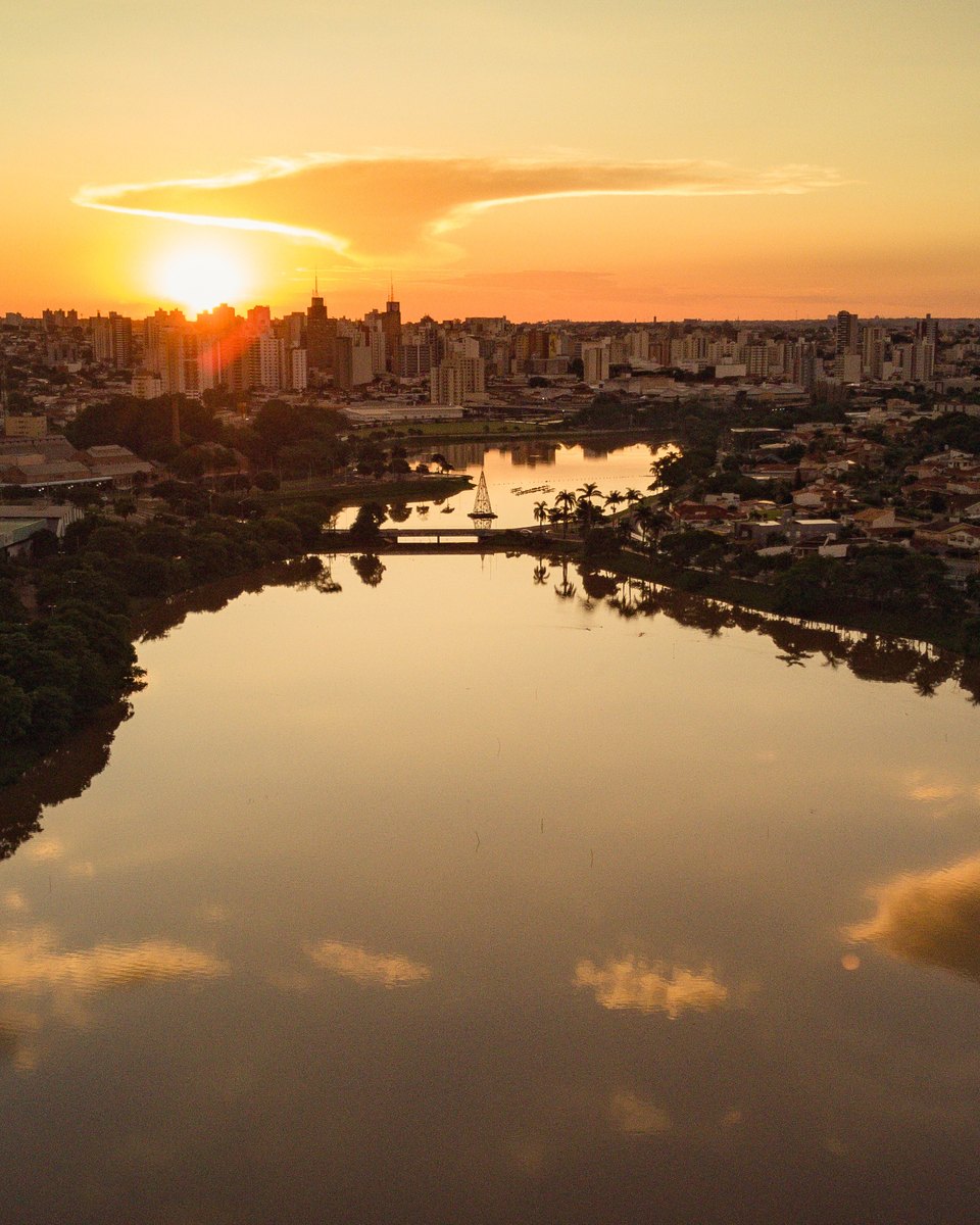 Represa Municipal de São José do Rio Preto vista de drone ao pôr do sol, com a cidade no horizonte.