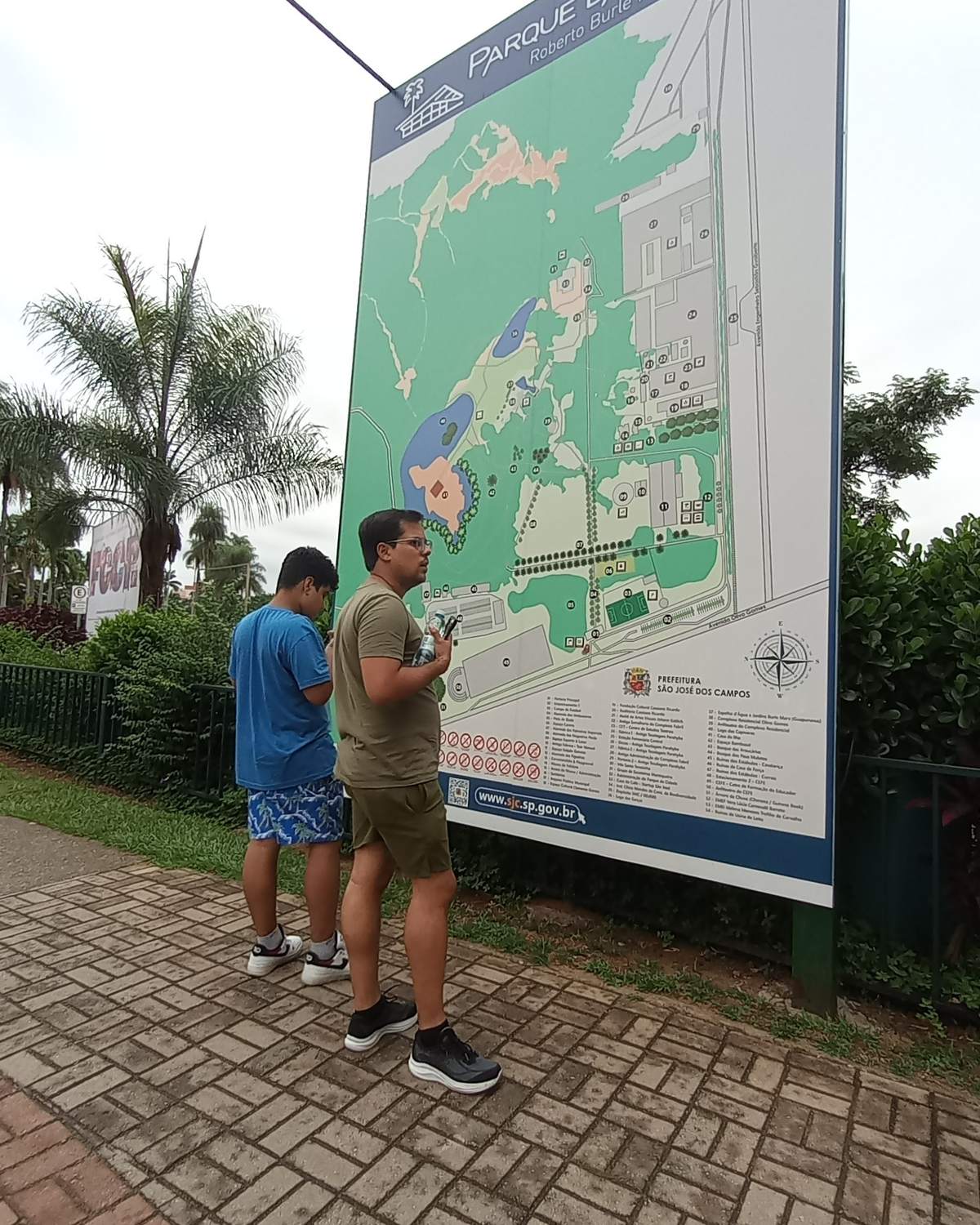 Dois rapazes consultando o mapa na entrada do Parque da Cidade, em São José dos Campos.