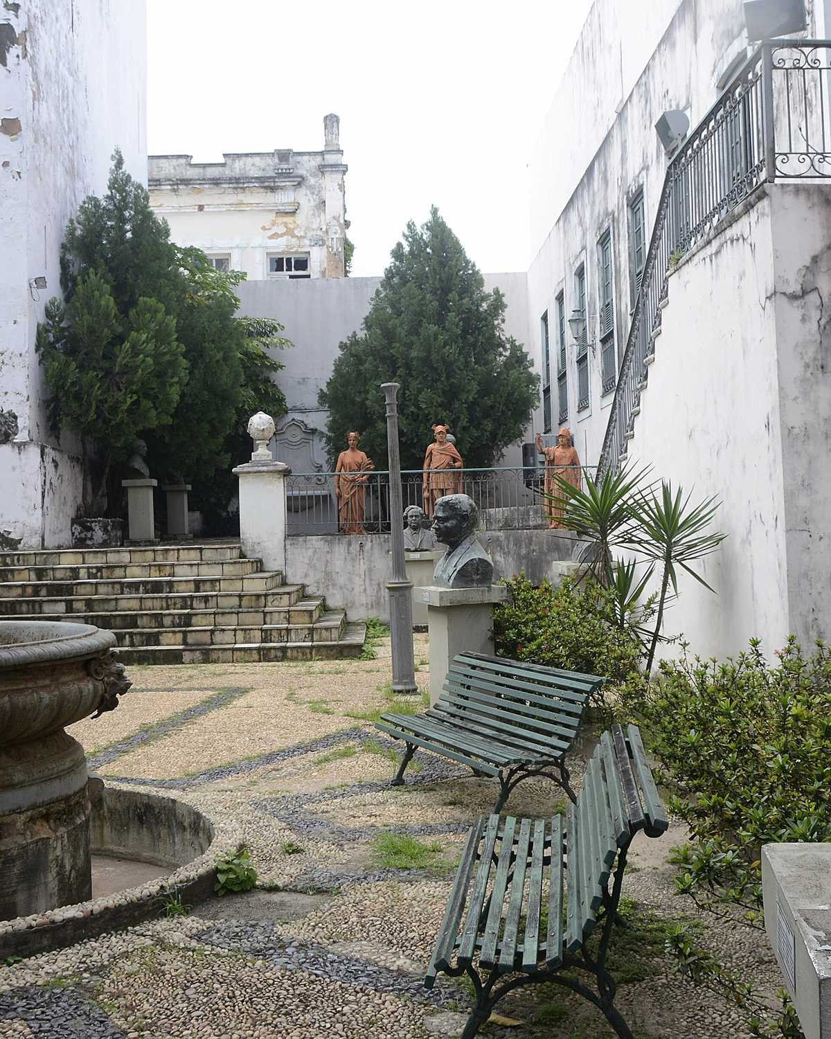 Pátio do Museu Histórico e Artístico do Maranhão, com chafariz de ferro, bancos verdes, bustos de bronze e esculturas junto à escadaria
