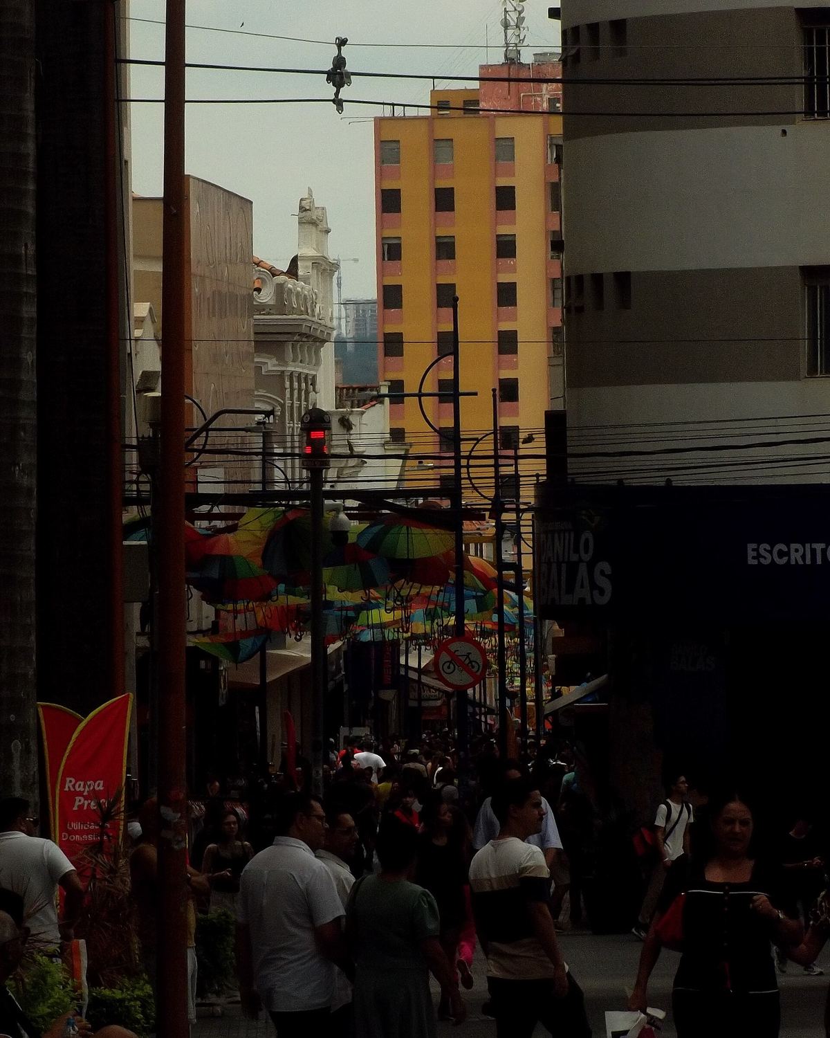 Calçadão da Braguinha cheio de gente fazendo compras, com guarda-chuvas coloridos pendurados sobre a rua e prédios ao fundo, no centro de Sorocaba.