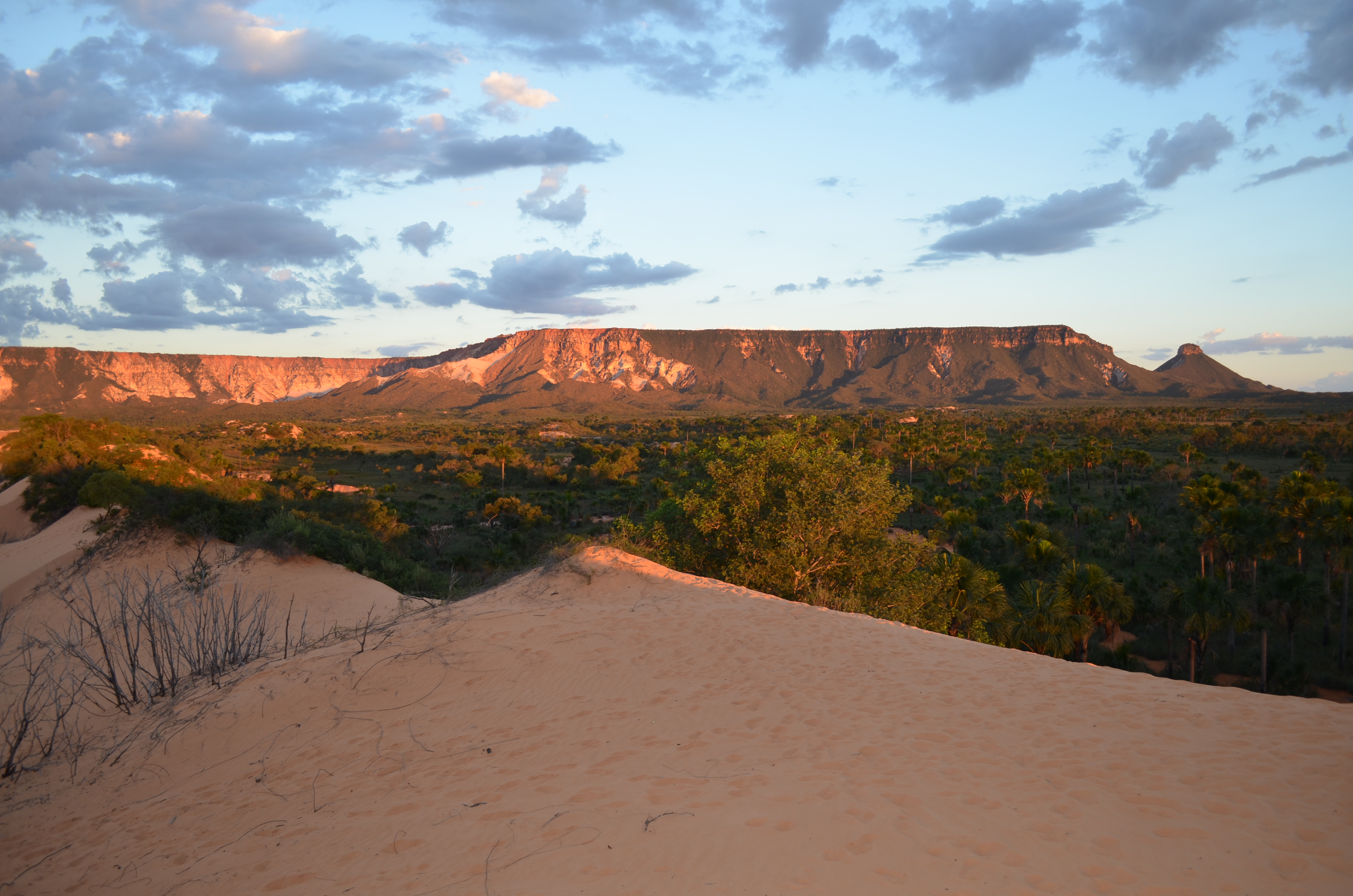 Vista da Serra do Espírito Santo ao entardecer, com dunas de areia e vegetação de cerrado em primeiro plano, no Jalapão