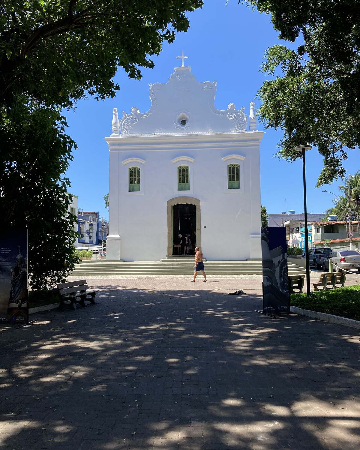 Fachada branca da Igreja de Nossa Senhora do Rosário, na Prainha, vista do largo arborizado.