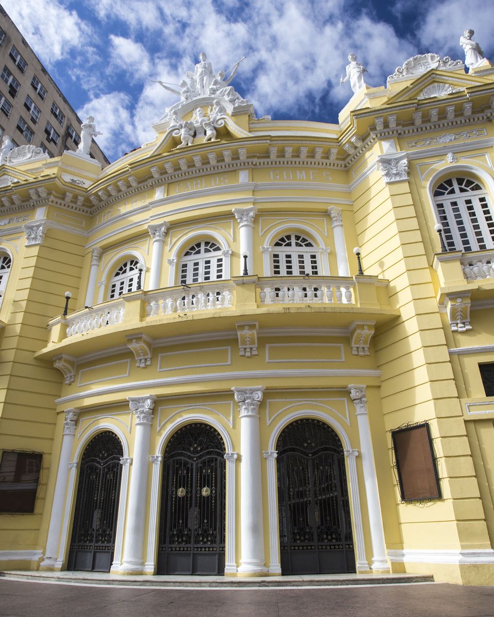 Fachada amarela e branca do Theatro Carlos Gomes, no Centro de Vitória, vista de baixo em dia de céu azul.