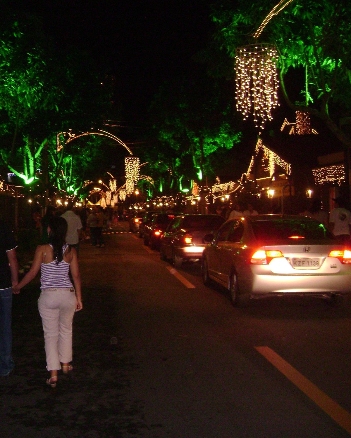 Rua de Volta Redonda iluminada para o Natal, com pessoas caminhando à noite.