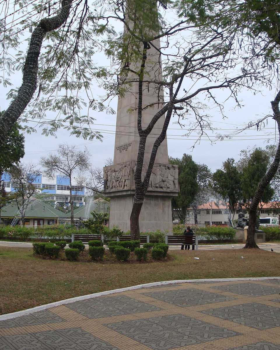 Praça Brasil, na Vila Santa Cecília, em Volta Redonda, com o obelisco, árvores e pessoas nos bancos.